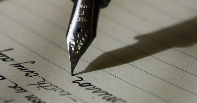 Picture of pen writing on a piece of paper, resembling someone writing his/her private keys for his cryptocurrency paper wallet.